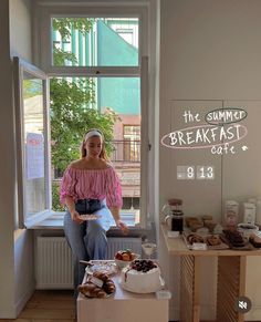 a woman standing in front of a table with pastries and donuts on it