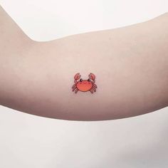 a crab tattoo on the left arm is shown in red and black ink, with an orange crab on it's side