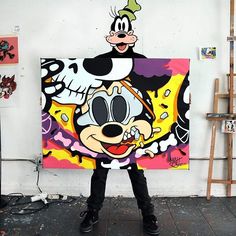 a man standing in front of a painting with goofy duck on it's face