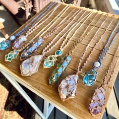 a wooden table topped with lots of necklaces