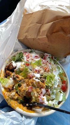 a salad in a white bowl with a brown paper bag next to it