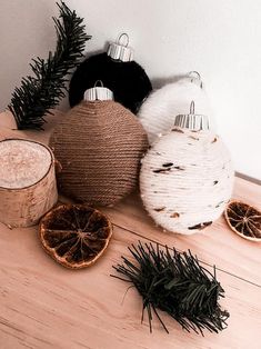 three ornaments are sitting on a table next to some pine cones and other decorations,