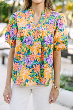 a woman wearing a colorful shirt and white pants