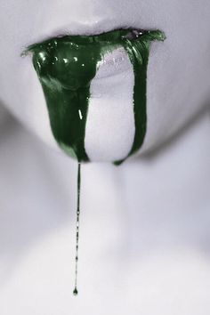 a person with green paint on their lips and tongue sticking out from under the lip