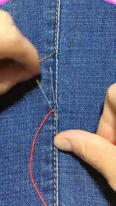 someone is stitching something on the back of a pair of jeans with red thread