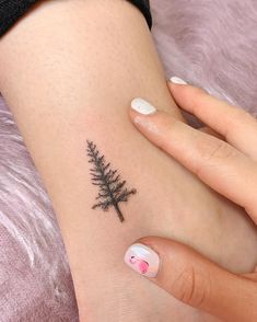 a small pine tree tattoo on the right side of the arm and left hand is shown