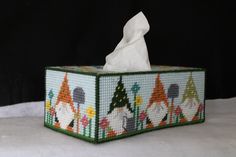 a tissue box is decorated with colorful christmas trees and gnomes on it, as well as a white napkin holder