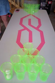 the table is covered with plastic cups and neon colored tape on it, as well as a pink number