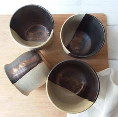 four brown and white bowls sitting on top of a wooden table next to each other