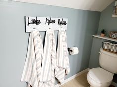 three towels hanging on the wall next to a toilet in a bathroom with blue walls