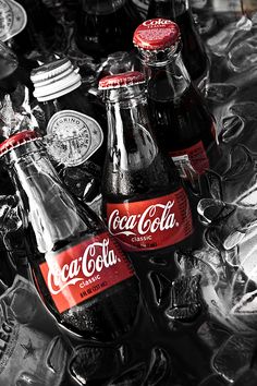 three coca cola bottles sitting on top of ice