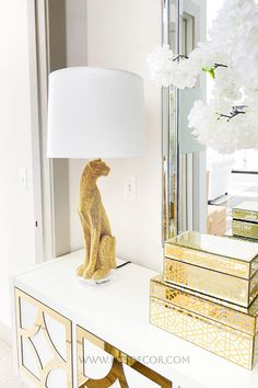 a lamp sitting on top of a white table next to a mirror and some boxes