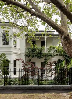 a white house with black iron fence and trees