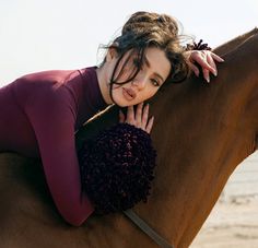 a woman is sitting on the back of a brown horse and posing for a photo