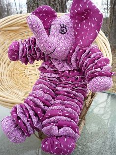 a purple teddy bear sitting on top of a table next to a wicker basket