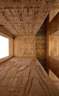 an empty room with egyptian paintings on the walls and ceiling in front of a window