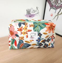 a floral print cosmetic bag sitting on top of a wooden table