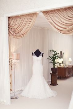 a wedding dress is displayed in front of a mirror