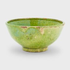 a green bowl sitting on top of a white table