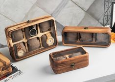 three wooden boxes with watches inside sitting on a table