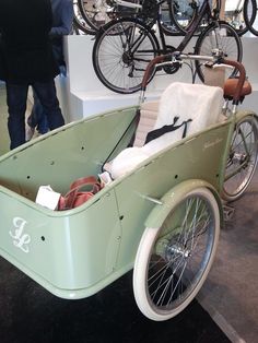 an old fashioned car is on display in a museum with people looking at bikes behind it