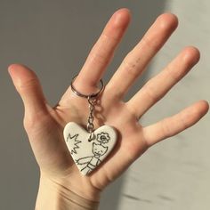 a hand holding a heart shaped keychain with a drawing of a man and woman on it