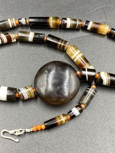 A beautiful Luk Mik Bead with rare shape and natural Pattern with natural Line in the center of Necklace along with 12 century khmer Angkor Empire Banded Agate Beads Luk mik means in Tibet (Goat's eye) or Ta Mik (horse eye) The beads got very shinny and smooth surface because of long passage of time using in necklaces and in prayers mala The agate beads were used in ancient times by rich Noble people of that time some orange color carnelian beads are used in necklace as spacers we provide fast a Onyx Gemstone Beaded Necklaces, Onyx Gemstone Beaded Necklace, Elegant Hand-strung Carnelian Beads, Beaded Agate For Jewelry Making, Polished Onyx Beaded Necklaces, Onyx Beaded Necklaces With Polished Round Beads, Hand-strung Agate Beaded Necklaces, Hand-strung Onyx Beaded Necklaces With Round Beads, Hand-strung Onyx Beaded Necklace With Round Beads