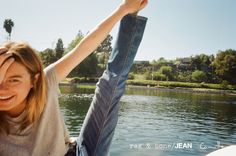 a woman sitting on the back of a boat with her arms in the air