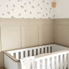 a white crib in a nursery with sheep wallpaper