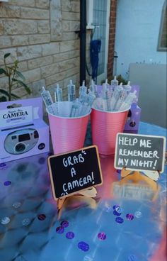 pink cups filled with toothbrushes sitting on top of a table next to a sign