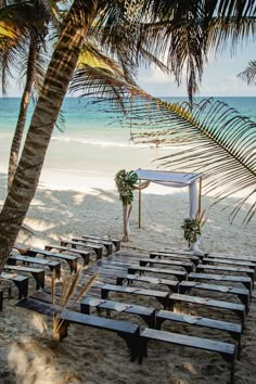 an outdoor ceremony setup on the beach with palm trees and chairs set up for it