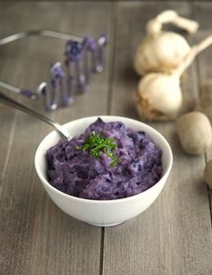 a white bowl filled with purple mashed potatoes