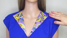 a mannequin wearing a blue dress with yellow and purple designs on it's collar