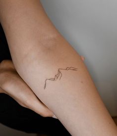 a woman's arm with a tattoo on it that is shaped like a mountain