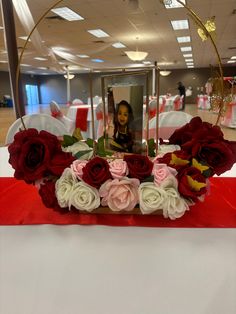 a red and white flower arrangement in front of a mirror on top of a table