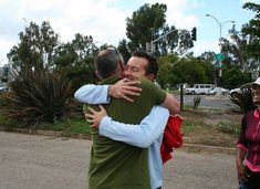 two men hugging each other on the street