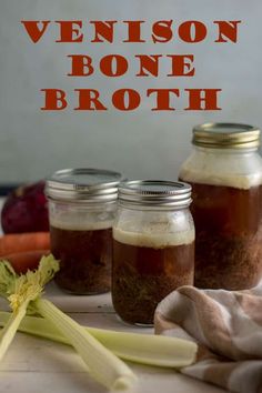 three mason jars filled with bone broth next to celery and carrots