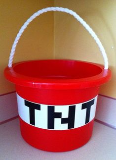 a red bucket with the word tht painted on it and a rope in front of it