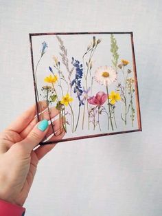 a woman holding up a card with wildflowers on it