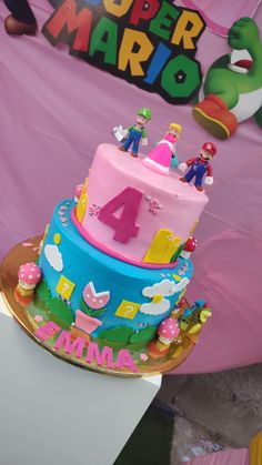 a birthday cake with mario and princess peaches on top is displayed in front of a super mario sign