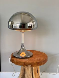 a table lamp sitting on top of a wooden stump next to a wall mounted mirror