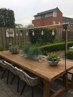 a wooden table sitting in the middle of a yard with potted plants on it