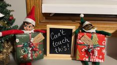 two elfs are holding presents next to a chalkboard with the words can't touch this