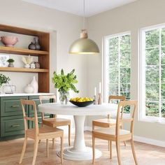 a dining room with green cabinets and white table