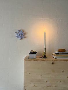 a lit candle sitting on top of a wooden dresser