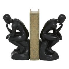 two black figurines sitting next to each other on top of a book shelf