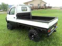 a white truck parked in the grass near a house