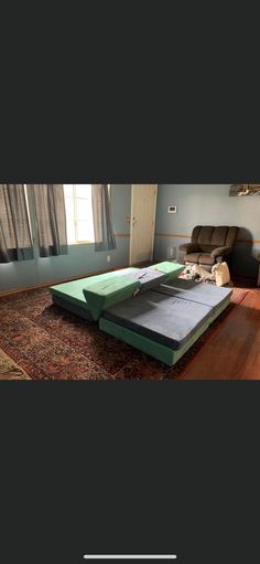 a bed sitting on top of a wooden floor in a living room next to a window