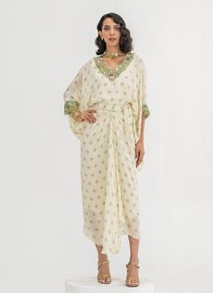 This elegant Ivory Embroidered Toga Cape Skirt Set is a timeless blend of sophistication and comfort. Crafted from soft crepe fabric, the set features a Ivory-colored, loose-fitting cape adorned with intricate floral embroidery around the neckline and cuffs. Paired with a wrap-style skirt that accentuates the waist and drapes effortlessly, it creates a flattering fit while ensuring easy movement. Ideal Indo-Western attire for home poojas, family gatherings, or festive occasions. Composition : Top and Skirt - Crepe Care: Dry Clean Only and Vacuum Storage This product can be customized for sleeves, blouse length and neckline Delivery : 4-6 weeks as the product is hand crafted. Check Size Guide or choose MySize for free customisation (All Sizes above XL can be made at 15% additional cost) For Festive Cream Kaftan With Resham Embroidery, Cream Kaftan With Resham Embroidery For Festive Occasions, Cream Resham Embroidery Kaftan For Festive Occasions, White Silk Kaftan For Festive Occasions, White Bohemian Embellished Sets, White Festive Kaftan For Spring, Bohemian Cream Sets For Eid, White Festive Spring Kaftan, White Traditional Drape Kaftan For Festive Occasions