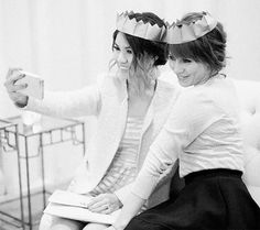 two women are sitting on a couch and one is holding a drink in her hand